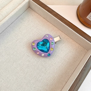 Detail of sweet heart-shaped duckbill clip with colorful rhinestones and blue gemstone