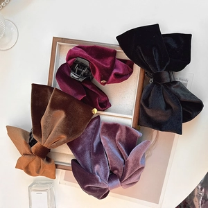 Détail de pinces à cheveux à nœuds en velours de diverses couleurs sur plateau bois