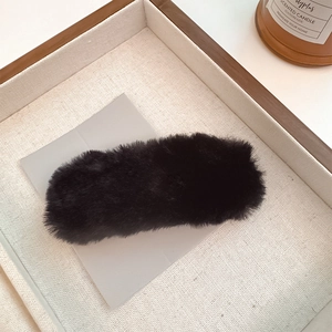 Close-up of black plush hair clip with soft fuzzy texture and elegant minimalist design