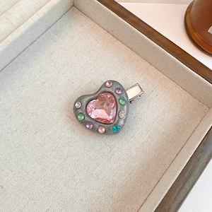 Detail shot of heart-shaped hair clip with colorful rhinestones in a wooden jewelry box