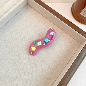 Detail of pink S-curve hair clip with colorful square and round rhinestones