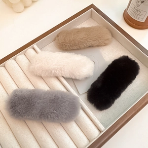 Detail view of plush faux fur hair clips in white, grey, khaki and black colors