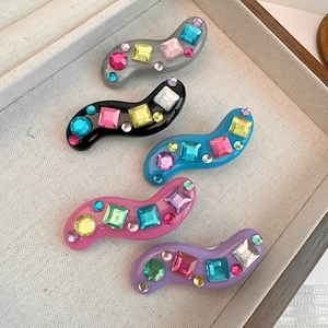 Five colorful S-shaped wave hair clips with rhinestones in a wooden display box