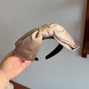 Detail of champagne satin bow headband featuring silk-like texture and elegant pleats
