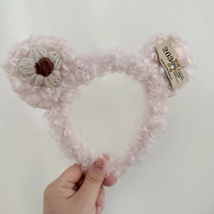 Close-up of pink sherpa bear ear headband with woven flower and fabric label detail