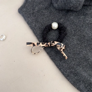 Leopard print bow hair scrunchie with large pearl accent on luxury neutral background