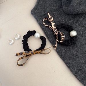 Detailed shot of leopard print bow hair tie with large pearl and silver hoop earrings