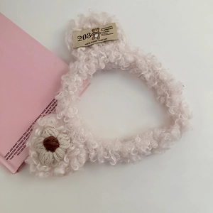 Detailed macro view of white plush bear headband with soft fleece texture and floral detail