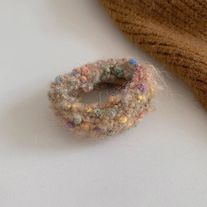 Detail eines Winter-Haargummis aus Plüsch mit bunten Punkten auf beigem Mohair