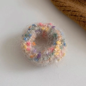 Detailaufnahme von Plüsch-Haargummi mit bunten Punkten, Stricktextur und Perlenverzierung