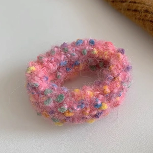 Nahaufnahme von rosa Plüsch-Haargummi mit bunten Punkten und weicher Strickstruktur