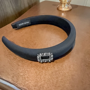 Detailed macro view of black padded headband with rectangle crystal buckle and handmade label
