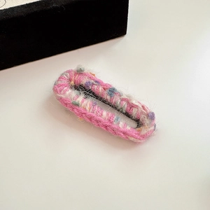 Vue macro d'une barrette carrée en laine mélangée rose tricotée à la main douce