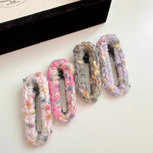 Gros plan de quatre barrettes en tricot fait main aux couleurs et textures mélangées