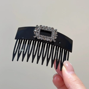 Detail view of a black hair side comb with sparkling rectangular rhinestone buckle
