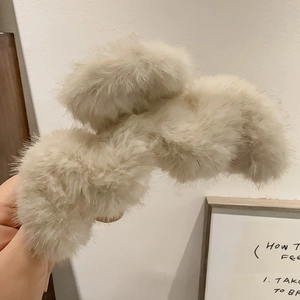 Détail de la pince à cheveux en fausse fourrure crème avec texture douce et prise forte