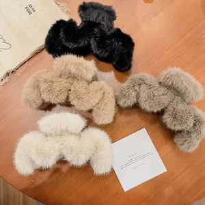 Vue à plat de quatre grandes pinces à cheveux en peluche en beige, fauve, marron et noir