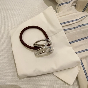 Minimalist elastic hair tie with an irregular silver metal ring on a white fabric base