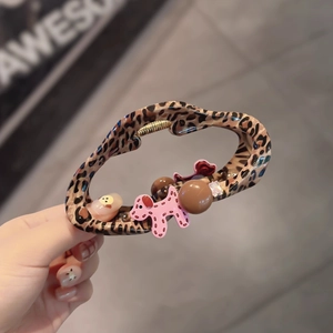 Close-up of leopard print hair claw clip featuring cute pink dog and gemstone charms