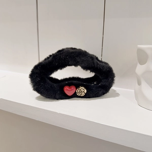 Detail of plush black hair claw clip with red heart and golden rose ornament
