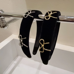 Détail d'un serre-tête en velours noir orné de nœuds métalliques dorés et argentés