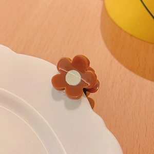 Primo piano di una mini pinza per capelli a fiore marrone su un piatto decorativo in porcellana