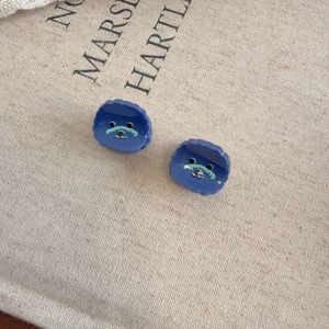 Dettaglio di mini mollette per capelli in resina blu con simpatici visi di nuvole cartoon