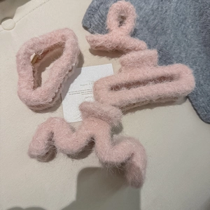 Macro view of four light pink plush hair claws in different shapes for winter