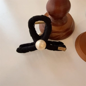 Minimalist black fabric hair claw clip with large pearl accent and gold brand tag