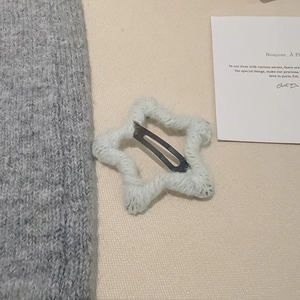 Détail d'une pince à cheveux étoile en laine tricotée blanche avec base en métal BB