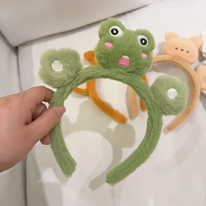 Dettaglio della fascia in peluche verde rana con graziosi ricami sul viso animale