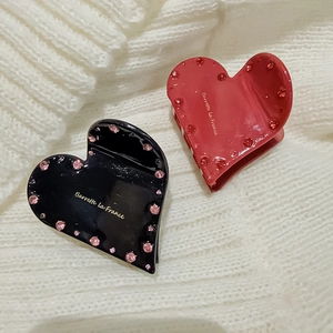 Detail von herzförmigen Haarklammern in Schwarz und Rot mit Strass und Goldtext