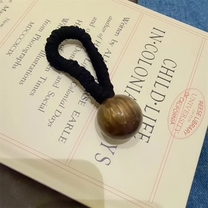 Elastic hair scrunchie with large tiger eye style bead on vintage book background