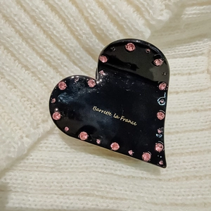 Detailaufnahme der herzförmigen Haarklammer mit rosa Strasssteinen und goldener Schrift