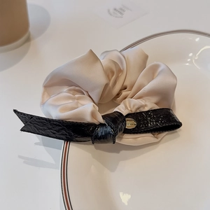 Elegant vintage faux leather bow hair tie in beige and black with gold charm detail
