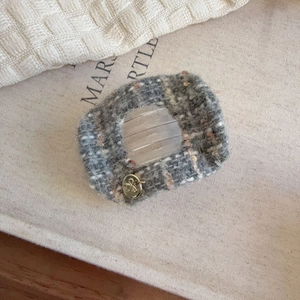 Close-up of grey tweed hair claw clip with golden bow charm and hollow design detail
