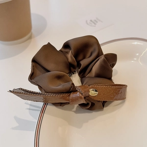 Elegant dark brown ribbon scrunchie with leather bow and gold buckle in a tea setting