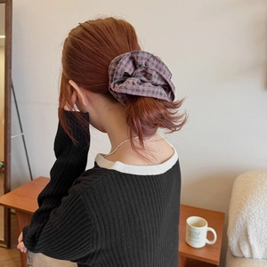 Close-up of pink and green plaid scrunchie styled in a low ponytail bun