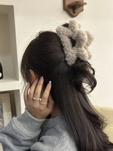 Dettaglio della clip per capelli a stella in peluche beige indossata sulla testa