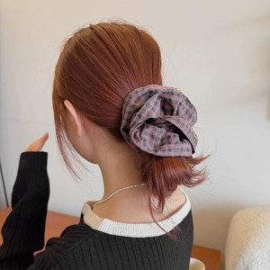 Detailed back view of a large pink and black plaid scrunchie styled on a woman's hair bun