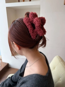 Dettaglio della clip per capelli in peluche rosso scuro su capelli castani scuri