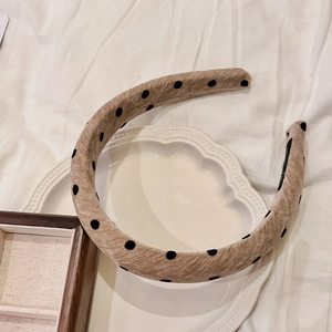 Close-up of French vintage velvet headband with black polka dots on beige fabric