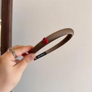 Brown padded sponge headband with a red heart detail and handmade label in a close-up view