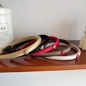 Detail view of five handmade heart-patterned headbands on a wooden shelf in a cozy setting