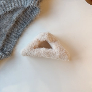 Nahaufnahme der weichen Plüsch-Haarklammer in Dreiecksform in Beige für den Winter