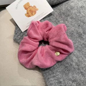 Detail of pink towel fabric scrunchie with round gold metal pendant charm