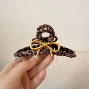 Elegant leopard print fabric hair claw clip with a 3D gold metal bow accent for women