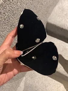 Detail of butterfly hair claw clip with black velvet, white trim, and five sparkling rhinestones