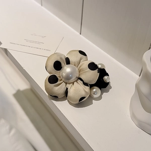 Chouchou fleur à pois avec perle blanche sur un support élégant et moderne