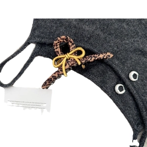 Elegant leopard print hair claw clip with golden bow accent on grey knit background